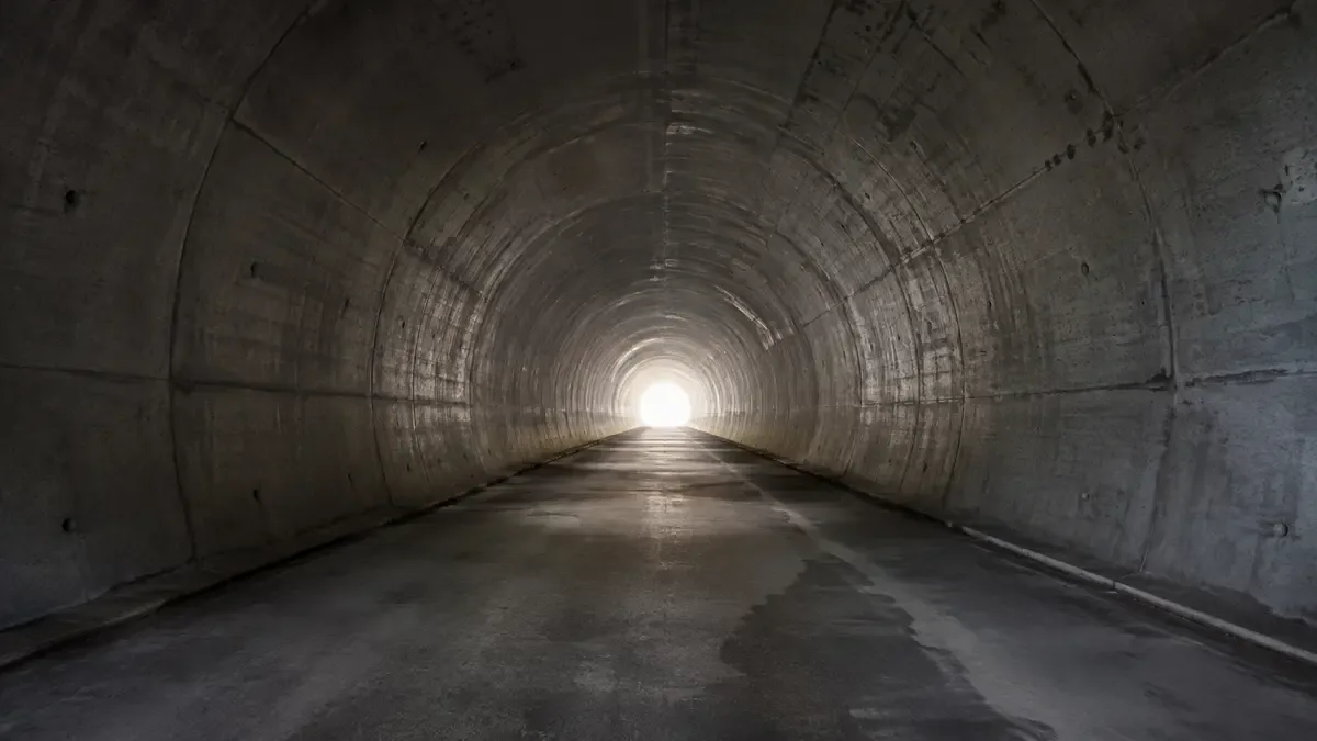 Tunel de hormigon largo y vacio con un circulo de luz al fondo