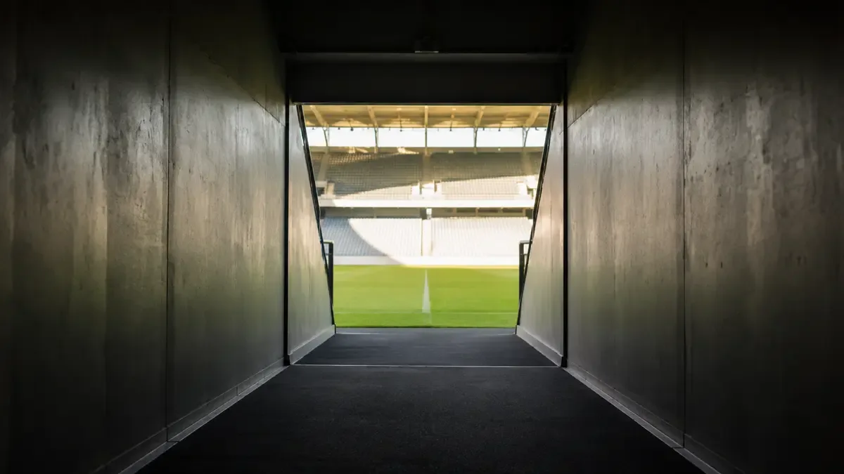Túnel de salida de un estadio hacia el campo de juego iluminado